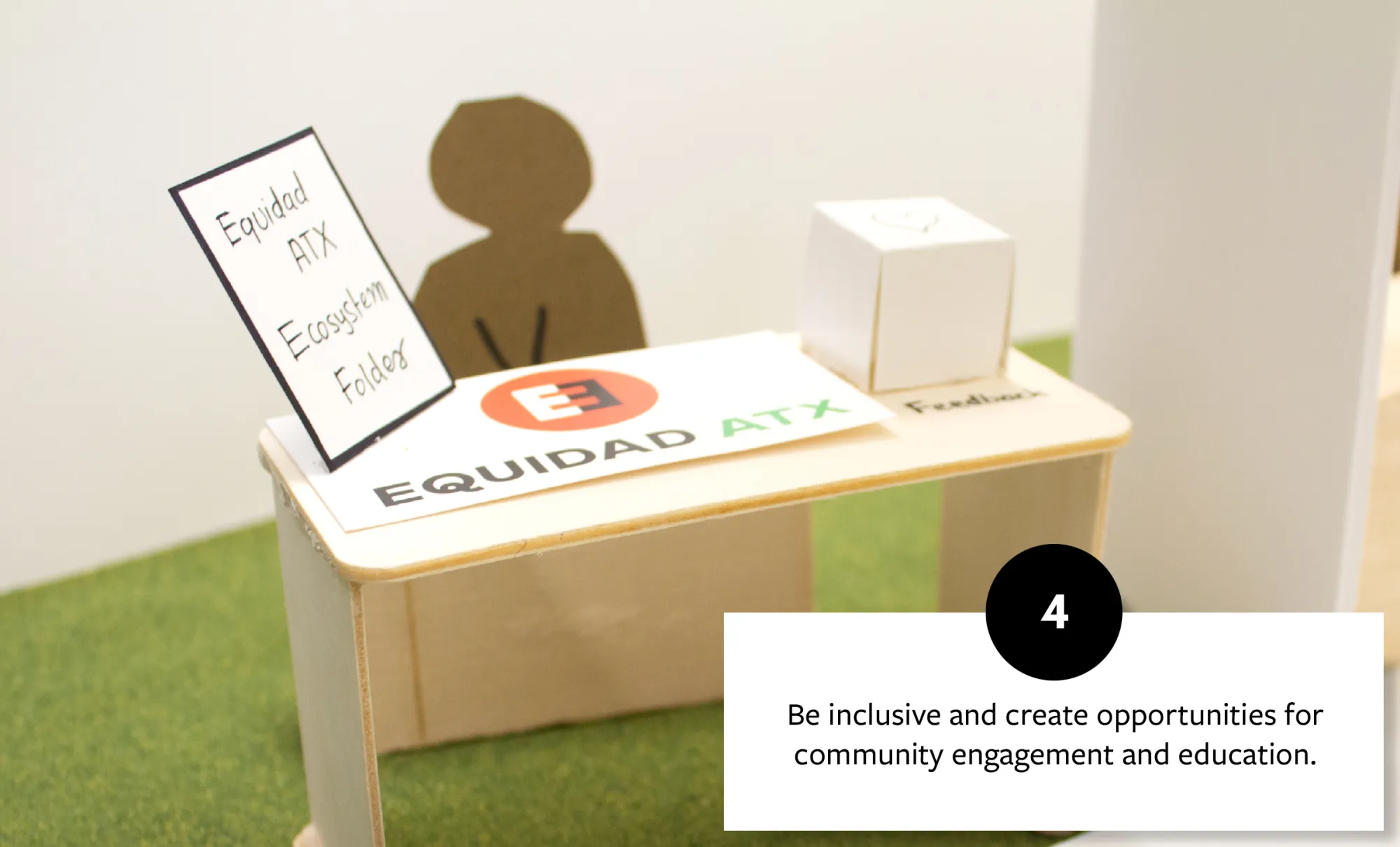 Model of a community engagement desk with an Equidad ATX sign, fostering inclusivity and opportunities for education and community involvement.