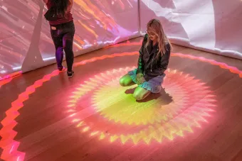 two Bee Cave BuzzFest attendees enjoy the Projection Mapped Cube inside the Hive Gallery, installed by UT Austin AET students