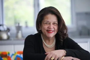 Photo of Cheryl Miller leaning forward and smiling in her office. The background has been blurred out.