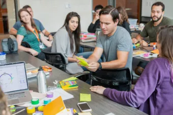 students at a table look at a student as he explains his ideas during a course for the first-of-its-kind Master of Design in Health at UT Austin