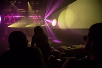 pink and yellow concert lights with the silhouettes of a small crowd in the foreground