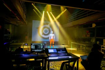 still of light show presentation from professor Matt Smith's live event engineering class. a mannequin stands in the middle of the PLAI lab while the light show happens around you
