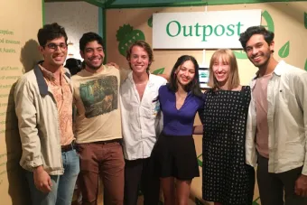 Group of students pose in front of BFA candidate exhibition Outpost, a place marginalized students can go to find meal kits