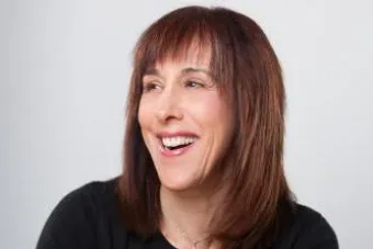 Portrait of Doreen Lorenzo smiling while holding her glasses in one hand