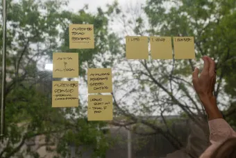 A hand rearranging sticky post-it notes on a window