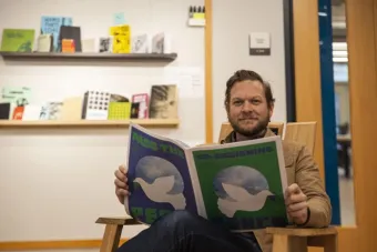 Director of the Center for Integrated Design Gray Garmon poses with a copy of a newsprint created in Co-Designing for Peace