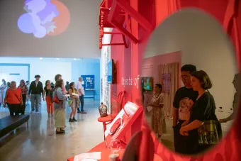 Becauseisms attendees seen in the reflection of a mirror interacting with Objects of Empathy installation