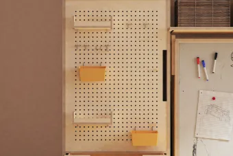 Close up of a workspace, focusing on a pegboard with organizational shelves.