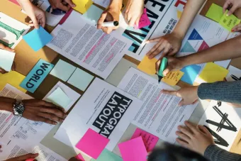 Overhead image of many different hands working on a group project about typographic layout