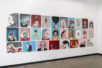 A wall installation of 25 mixed-media artworks arranged in a grid pattern. Each piece features surreal and expressive portraits of figures with Day of the Dead-inspired makeup, abstract backgrounds, and handwritten text elements. The collection incorporates bold colors, intricate patterns, and symbolic imagery, exploring themes of identity, transformation, and cultural heritage.