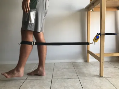 a person tests the MMT prototype on their leg at home by connecting it to a table in their kitchen