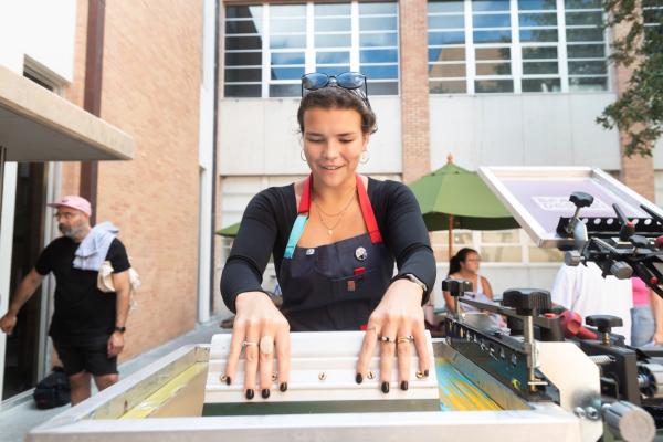 Master of Fine Arts in Design student enjoying a screen printing workshop outdoors with her MFA cohort at UT Austin