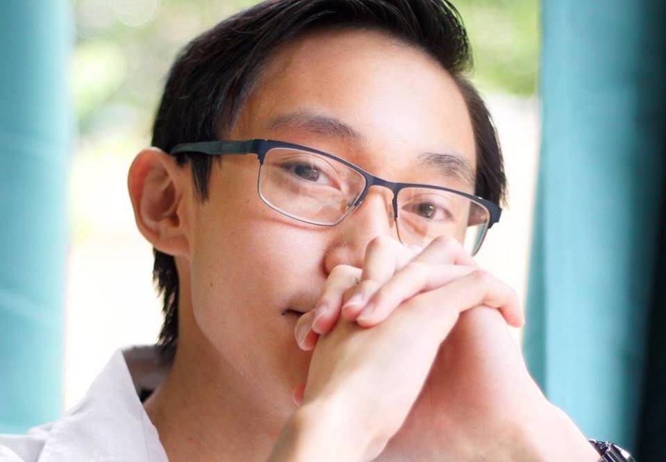 headshot of AET senior Alex Kong with his hands folded and resting on his mouth