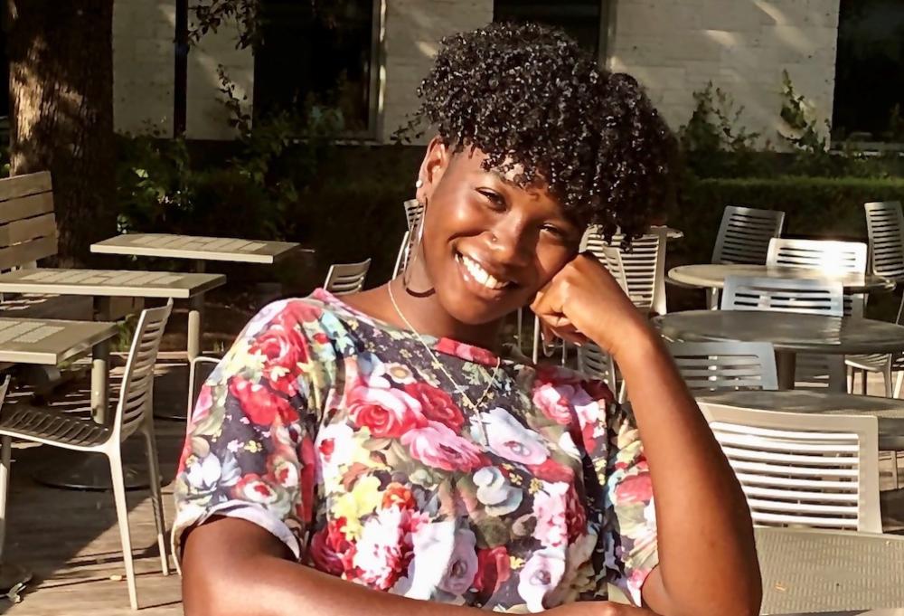 AET senior DeSha Bass-McClellan smiling with her head resting on her fist outside the WCP Student Activity Center