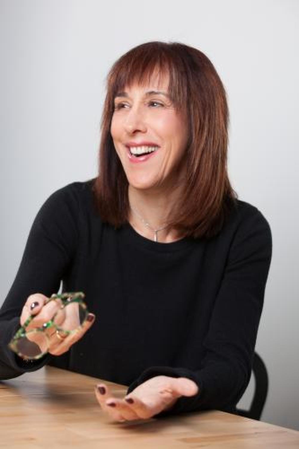 Portrait of Doreen Lorenzo smiling while holding her glasses in one hand