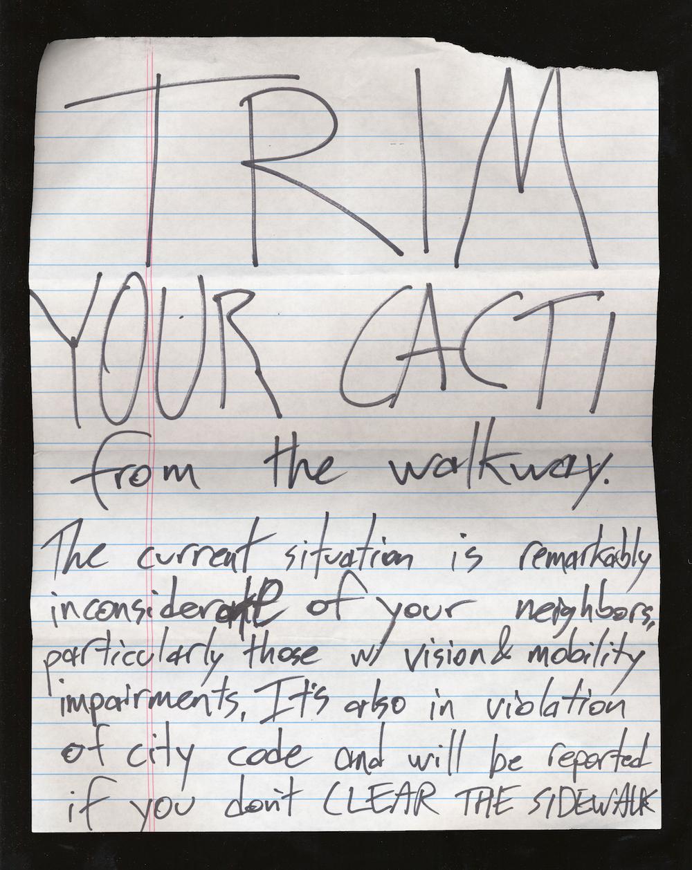  A note that reads TRIM YOUR CACTI from the walkway. The current situation is remarkably inconsiderate of your neighbors, particularly those with vision & mobility impairments. It’s also in violation of city code and will be reported."