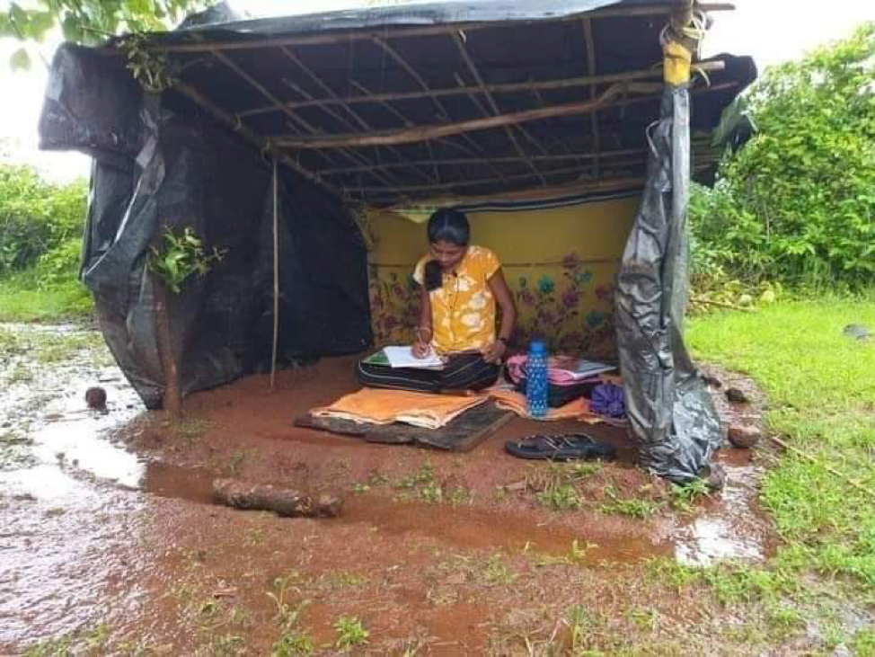 a young woman studying to be a doctor in a shed made of tarps with a dirt floor. It has been raining, so she is surrounded by mud