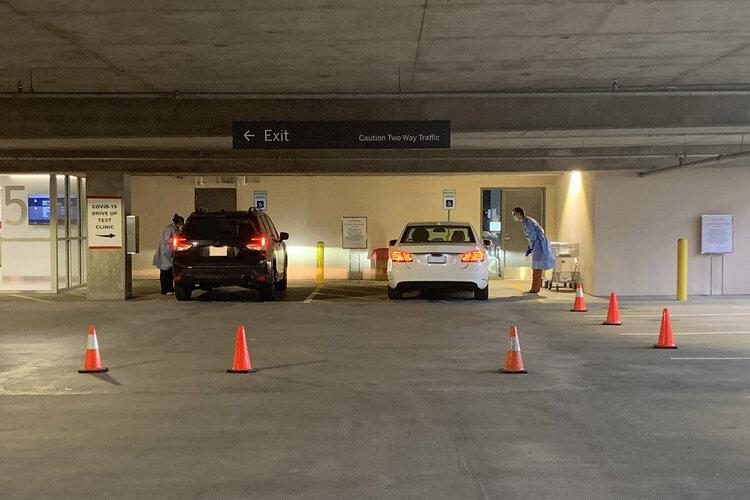 Two cars whose passengers are getting drive-thru tested for COVID-19