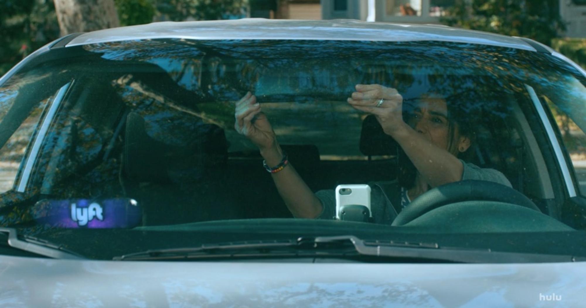 Source: Hulu/Ramy TV Series still image from TV series Ramy. a woman adjusts the rear-view mirror in her car. a Lyft logo is visible in the lower left corner of the windshield