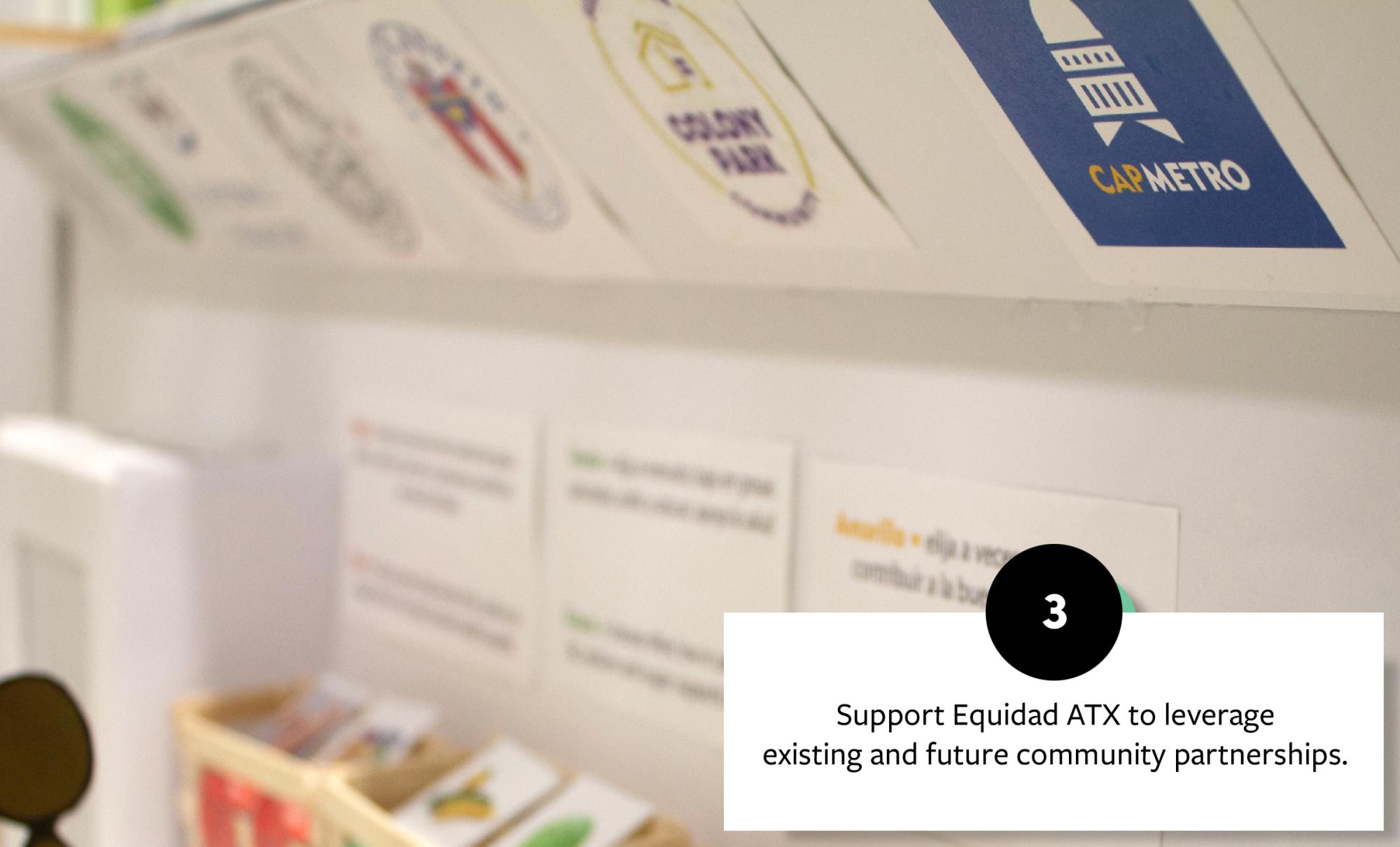 Display shelf with community partner logos, highlighting support for Equidad ATX in building partnerships, with informational signage in the background.
