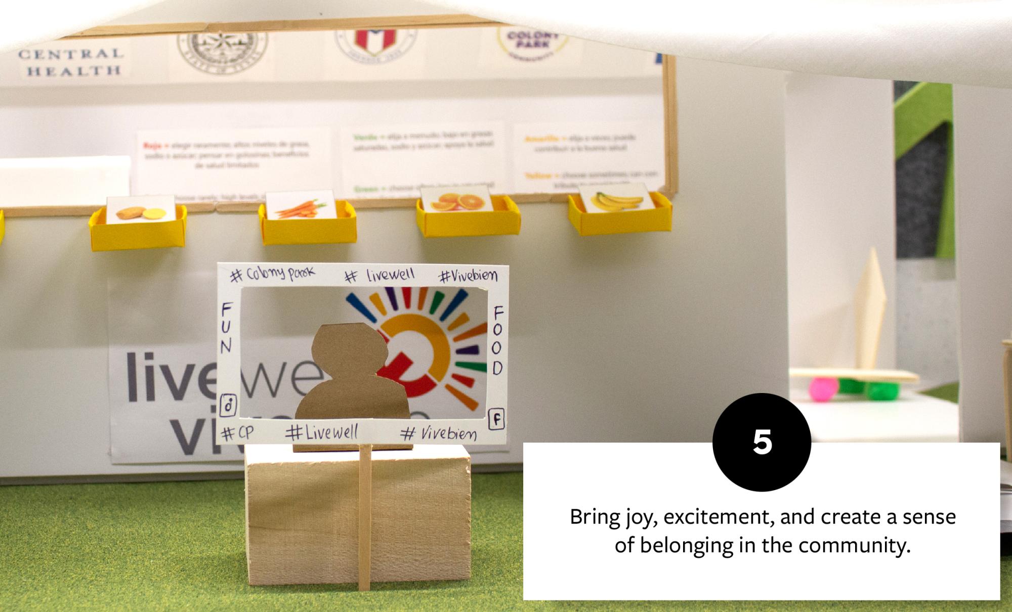 Interactive display with a cardboard figure and a cut-out photo frame, promoting a sense of community and engagement with joyful elements like colorful food images.