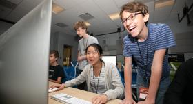 High school students smiling and laughing as they play an original video game created during SDCT's Summer Design Camp for teens