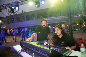 Arts and Entertainment Technologies professor Matt Smith and student Jayden Chavez smile at the camera while programming lighting at the 2022 Bee Cave BuzzFest