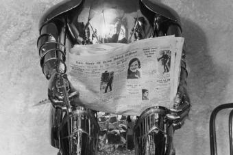black and white photo of tin man sculpture reading a newspaper