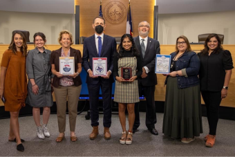 Ashwara Pillai, first place winner of the first Travis County "I Voted" sticker design contest, standing next to members of the Travis County Clerk Elections Division 