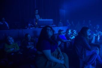 students are bathed in blue light as they watch a concert light show