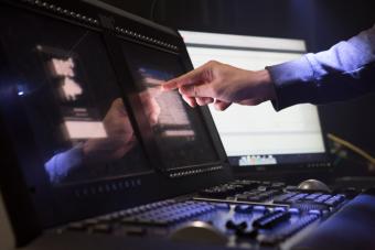 an extended hand touching the screen of a theatrical lighting programming board