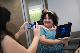 Student posing with her game design artwork on a laptop