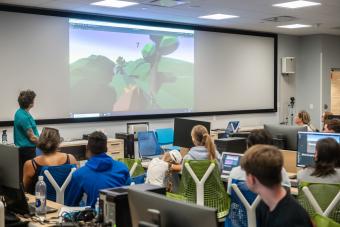 People sitting together to watch a student's game design demo