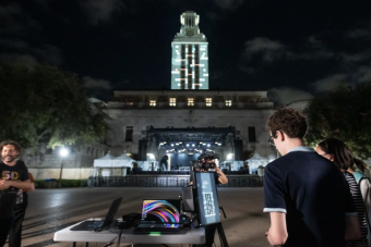 Photo of student playing "Tower Tumble," an original video game designed by AET students and faculty, on the UT Austin Tower through projection mapping