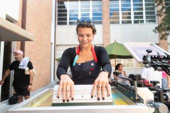 Master of Fine Arts in Design student enjoying a screen printing workshop outdoors with her MFA cohort at UT Austin