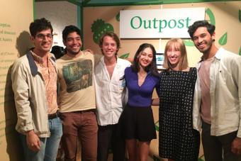 Group of students pose in front of BFA candidate exhibition Outpost, a place marginalized students can go to find meal kits