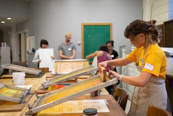 Design student screen printing a poster in the Design Lab at UT Austin