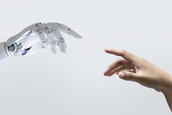 A robot hand reaching out to a human hand with their fingers almost touching