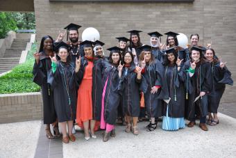 Master of Arts in Design focused on Health Class of 2023 graduates making the hook em hand sign outside the Kendra Scott Center