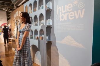 BFA Design 2022 graduate Gia Kanani Poblete smiling in front of her senior exhibition Hue Brew