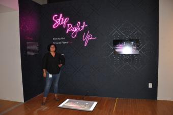 2022 MFA Design graduate Sarah Martinez posing next to her exhibition Step Right Up