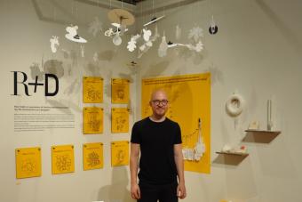 2022 MFA Design graduate Christoph Sokol posing next to his exhibition R and D