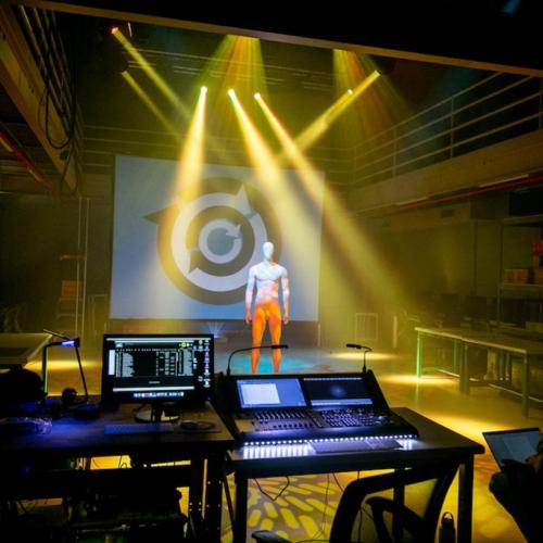 still of light show presentation from professor Matt Smith's live event engineering class. a mannequin stands in the middle of the PLAI lab while the light show happens around you