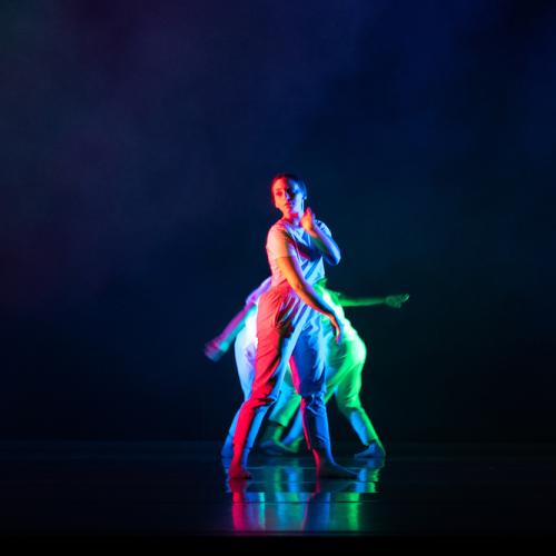 a dancer onstage at Evolution 2022 against a dark background, which makes the brightly colored lighting design stand out