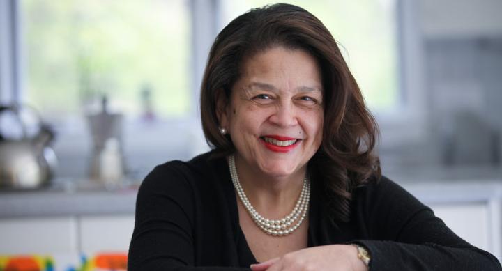 Photo of Cheryl Miller leaning forward and smiling in her office. The background has been blurred out.