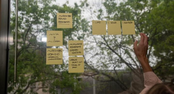 A hand rearranging sticky post-it notes on a window