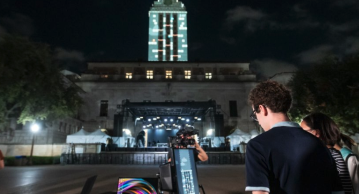 Photo of student playing "Tower Tumble," an original video game designed by AET students and faculty, on the UT Austin Tower through projection mapping